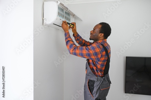 Professional repairman installing air conditioner in a room