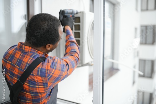 a professional electrician man is fixing the heavy air conditioner