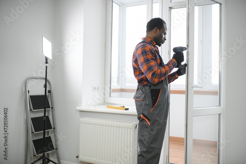 a african repairman repairs, adjusts or installs metal-plastic windows in the apartment