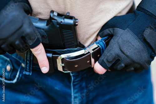 the guy puts the gun in the holster close-up photo