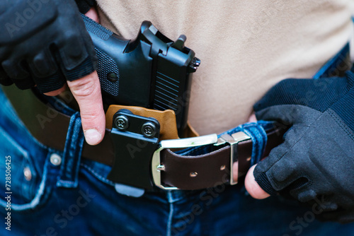 Fotografía the guy puts the gun in the holster close-up