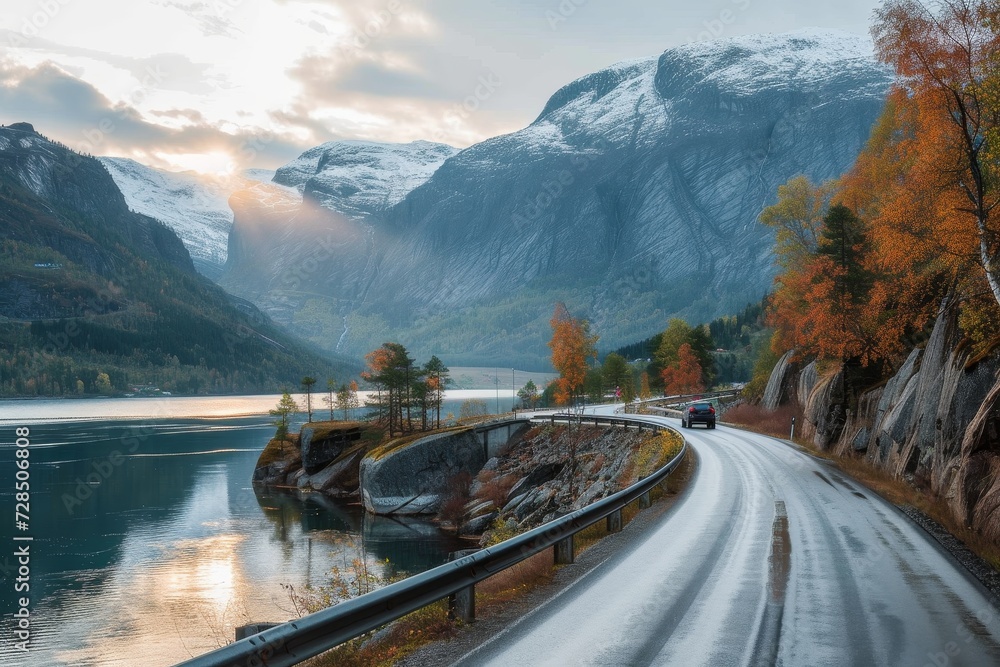 A scenic road winds through a vibrant autumn landscape, framed by towering mountains and a tranquil lake, beckoning travelers to explore the breathtaking outdoor beauty