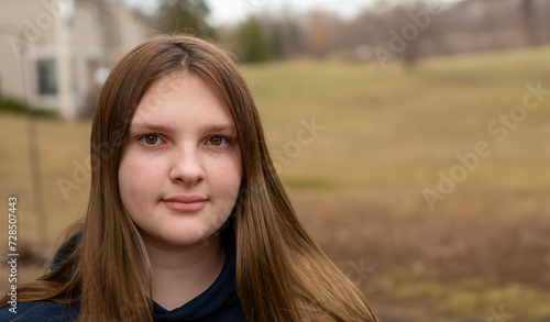Teen girl looking at the camera outdoors on an overcast day with room for copy