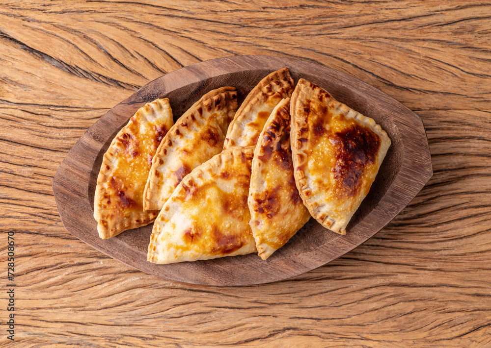 Typical brazilian snack baked pastel on a plate over wooden table Typical brazilian snack baked pastel on a plate over wooden table