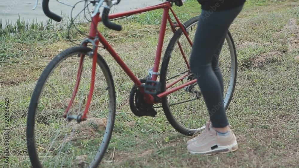 Happy young Asian woman while riding a bicycle in a city park. She smiled using the bicycle of transportation. Environmentally friendly concept. Happy young Asian woman while riding a bicycle in a city park. She smiled using the bicycle of transportation. Environmentally friendly concept.