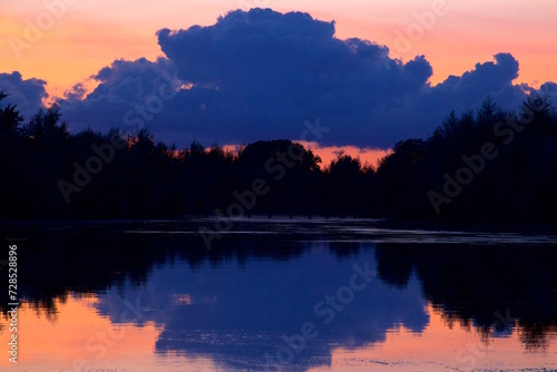 Blue clouds at dusk reflected in the forest lake water