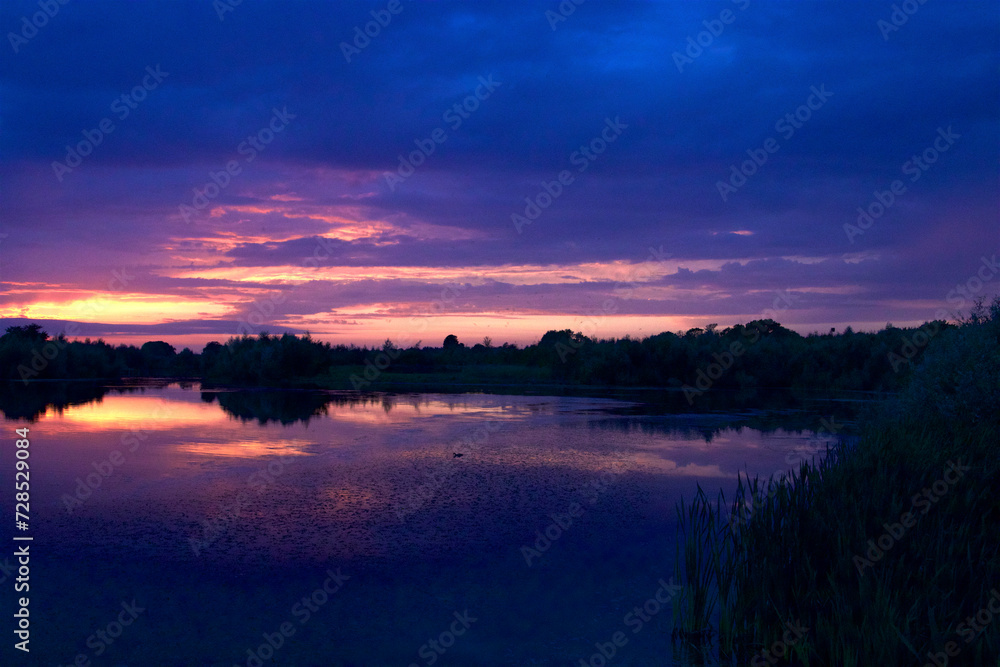 Blue purple sky at dusk by the forest lake