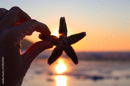 Starfish in hand. Sunset on the sea.
