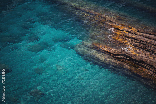 Aerial view of calm turquoise sea water and rocks from molten lava from drone. Pattern of sea surface and rocky shore. Liguria, Italy. turquoise water of Ligurian sea. photo