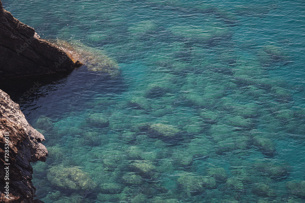 Aerial view of calm turquoise sea water and rocks from molten lava from drone. Pattern of sea surface and rocky shore. Liguria, Italy. turquoise water of Ligurian sea. Aerial view of calm turquoise sea water and rocks from molten lava from drone. Pattern of sea surface and rocky shore. Liguria, Italy. turquoise water of Ligurian sea.
