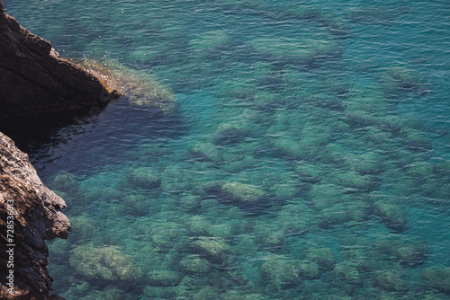 Aerial view of calm turquoise sea water and rocks from molten lava from drone. Pattern of sea surface and rocky shore. Liguria, Italy. turquoise water of Ligurian sea. © Cristina
