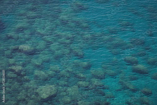 Aerial view of calm turquoise sea water and rocks from molten lava from drone. Pattern of sea surface and rocky shore. Liguria, Italy. turquoise water of Ligurian sea.