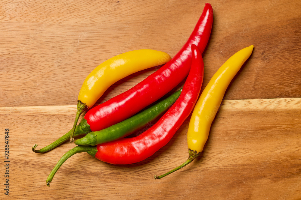 Hot peppers of different colors on a wooden chopper