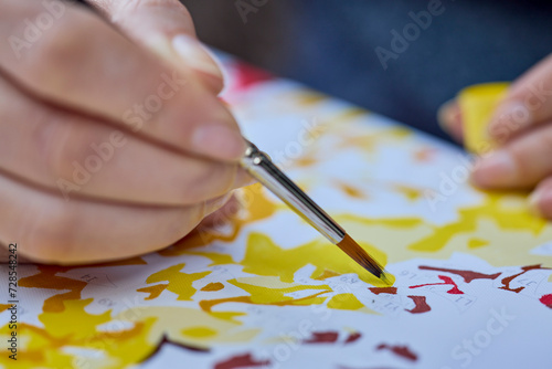 a woman's hand holding a brush and painting on a canvas to learn to paint.