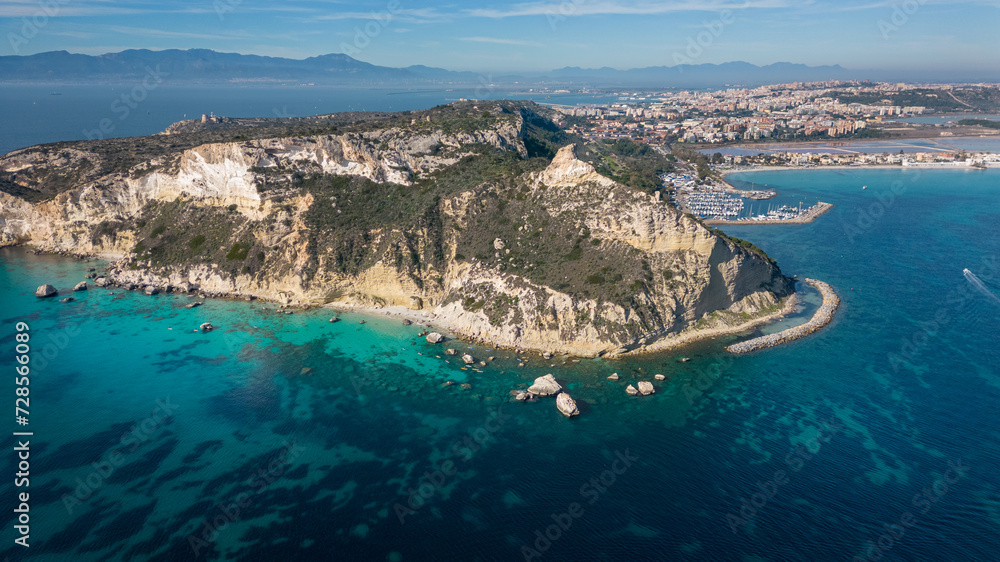 Aerial view with drone of the Sella del Diavolo in Cagliari. Sunny day, crystal clear sea with boats.