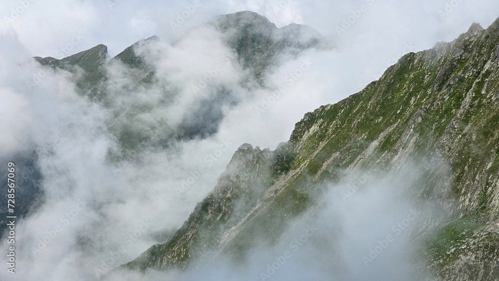 Majestic mountain peak shrouded in wispy clouds, serene beauty.