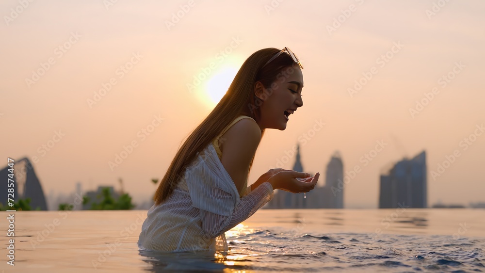 smiling laugh happiness summer vacation moment asian woman yellow bikini hand hold sun glasses while enjoy weekend leisure summer moment laugh smile cheerful on rooftop swimming pool sunset