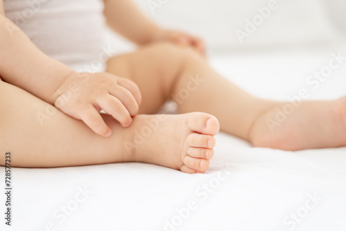 Fototapet close-up of legs and arms of a small child a girl or a boy in a white bodice on