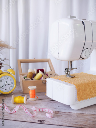 Foto Close up sewing machine working with yellow fabric, sewing accessories on the table, stitch new clothing