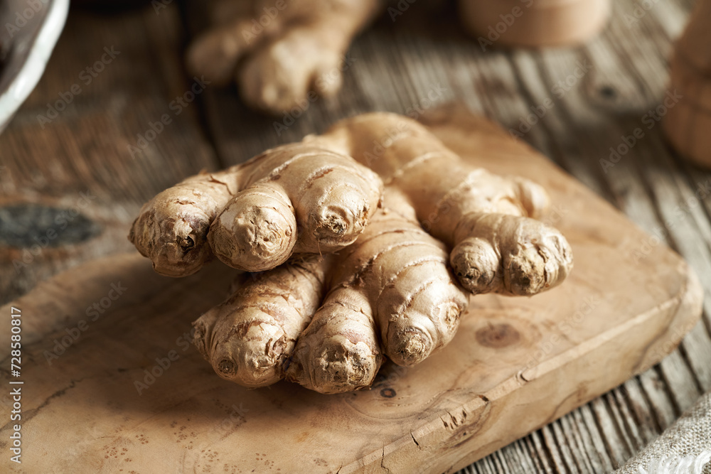 Fototapeta premium Fresh ginger root on a wooden cutting board, close up