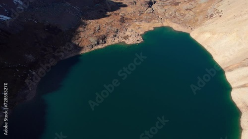 drone shot panning up revealing the large lake placed in the valley of a mountain photo