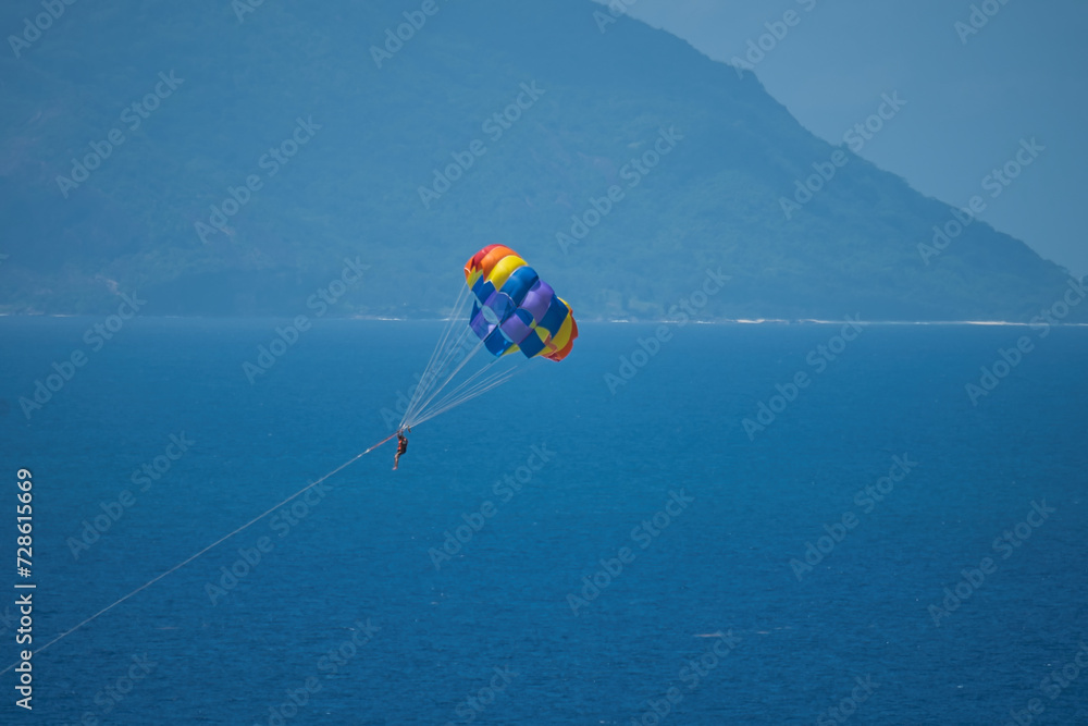 Single person paragliding from boat at beau vallon beach, Mahe, Seychelles Single person paragliding from boat at beau vallon beach, Mahe, Seychelles