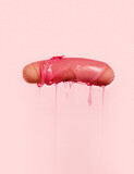 Sausage with dripping pink sauce on pink background.