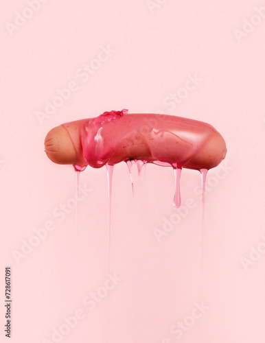 Sausage with dripping pink sauce on pink background. photo
