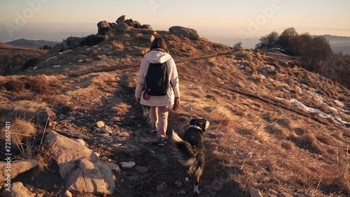A girl walking in the mountains with her dogs at sunset.