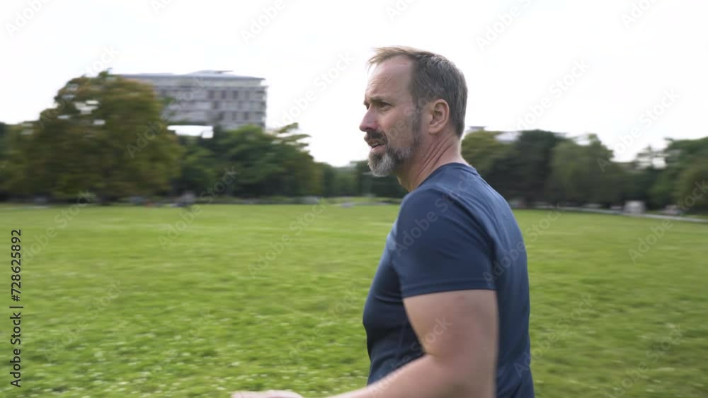 A handsome middle-aged Caucasian man looks around in confusion in a park on a sunny day - camera spins A handsome middle-aged Caucasian man looks around in confusion in a park on a sunny day - camera spins