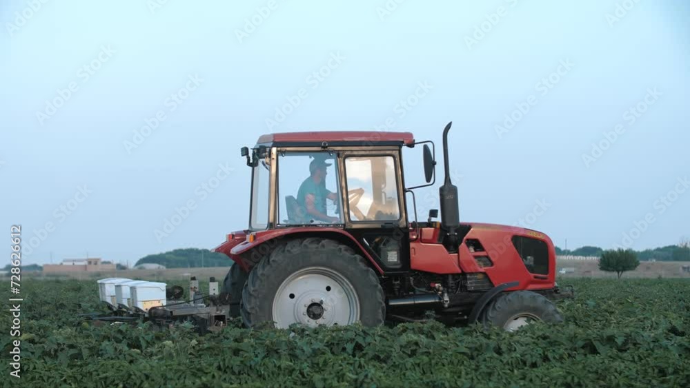 Pesticide Sprayer Tractor working on a large green field. following on the side a tractor spraying wheat field against diseases. Farmer spraying vegetable fields. Pesticide Sprayer Tractor working on a large green field. following on the side a tractor spraying wheat field against diseases. Farmer spraying vegetable fields.