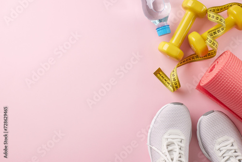 Vigorating workouts for a healthy you. Top view photo of trendy sneakers, yellow dumbbells, measure tape, yoga mat, water bottle on pastel pink background with advert panel