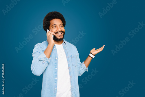 A young African-American man is engaged in a phone call, gesturing with his hand as if explaining something. The image captures the ease of modern communication and the casual multitasking it enables. photo