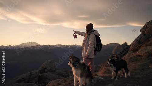 A girl walking in the mountains with her dogs at sunset.