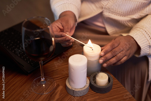 High angle closeup of Black adult woman lighting candles on table for relaxing evening at home copy space