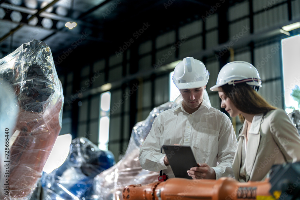 Business engineers meet and check control heavy machine robot arm. Diverse Team of Industrial Robotics Engineers Gathered Around machine. Professional Machinery Operator Use Industrial Digital Tablet. Business engineers meet and check control heavy machine robot arm. Diverse Team of Industrial Robotics Engineers Gathered Around machine. Professional Machinery Operator Use Industrial Digital Tablet.