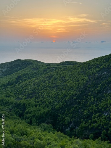 Mediterranean sunset from the Agalas viewpoint. Sitting and watching sunset in Zakynthos, Greece. Sunset pine trees, olive groves and sea view on a greek island. © Chawran