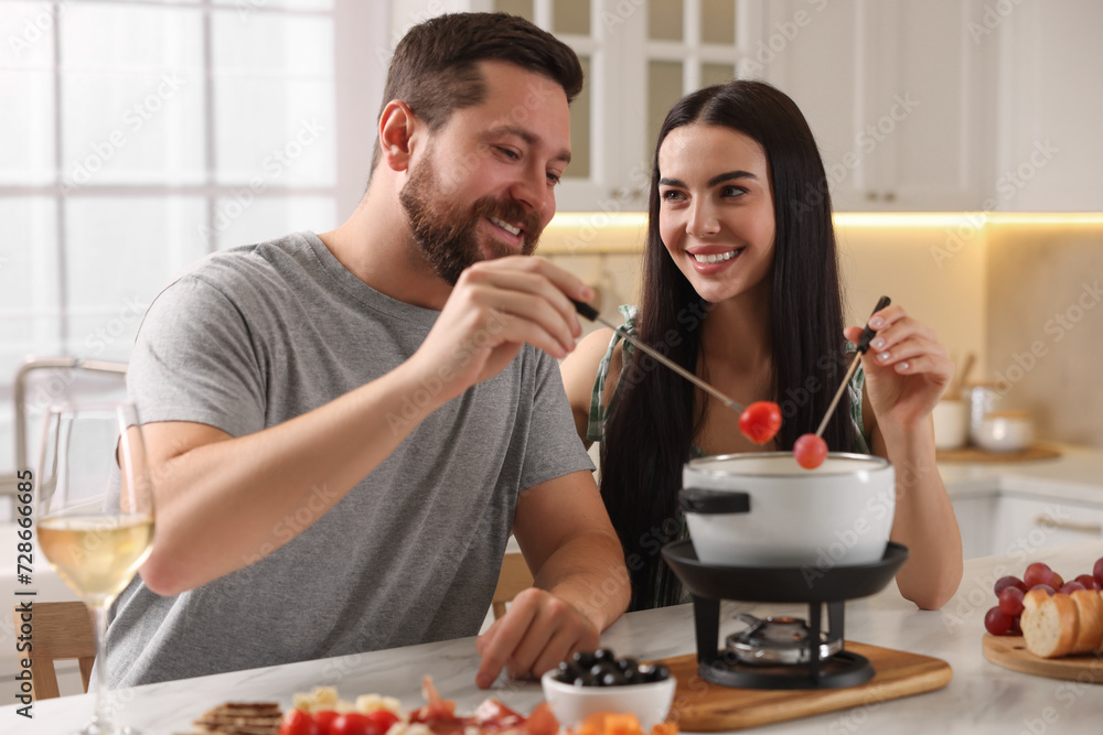 Affectionate couple enjoying fondue during romantic date in kitchen Affectionate couple enjoying fondue during romantic date in kitchen