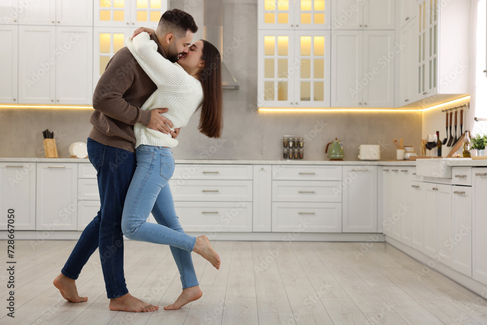 Affectionate young couple kissing in kitchen. Space for text Affectionate young couple kissing in kitchen. Space for text