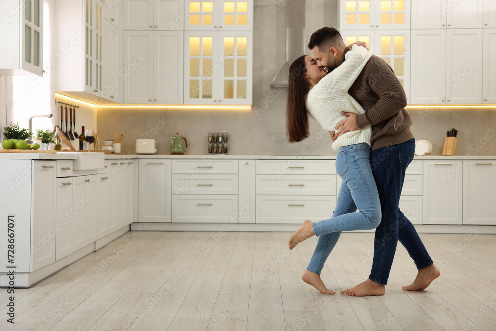 Affectionate young couple kissing in kitchen. Space for text Affectionate young couple kissing in kitchen. Space for text