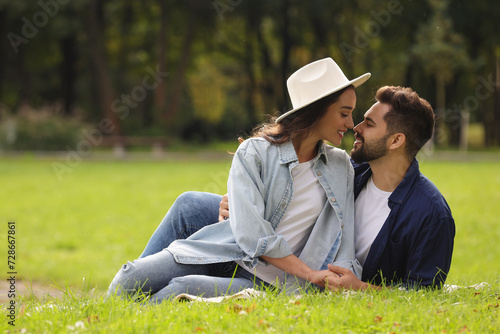 Beautiful couple spending time together in park, space for text