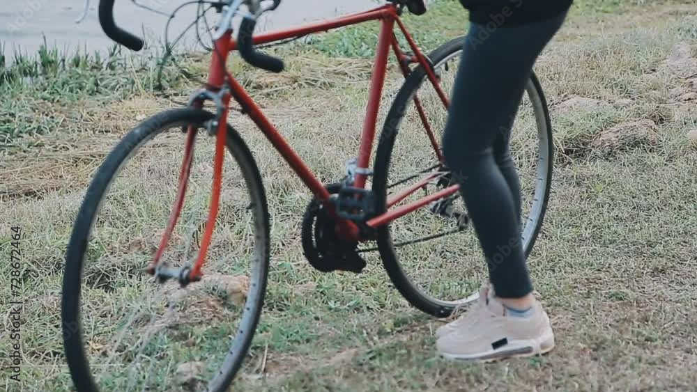 Happy young Asian woman while riding a bicycle in a city park. She smiled using the bicycle of transportation. Environmentally friendly concept. Happy young Asian woman while riding a bicycle in a city park. She smiled using the bicycle of transportation. Environmentally friendly concept.