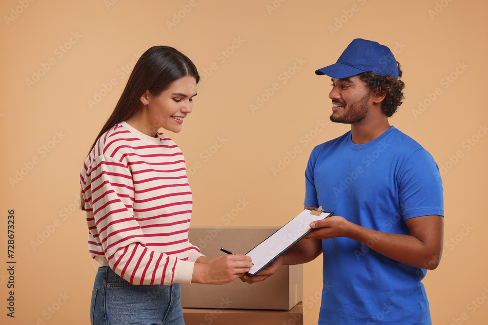 Smiling woman signing order receipt on light brown background. Courier delivery Smiling woman signing order receipt on light brown background. Courier delivery