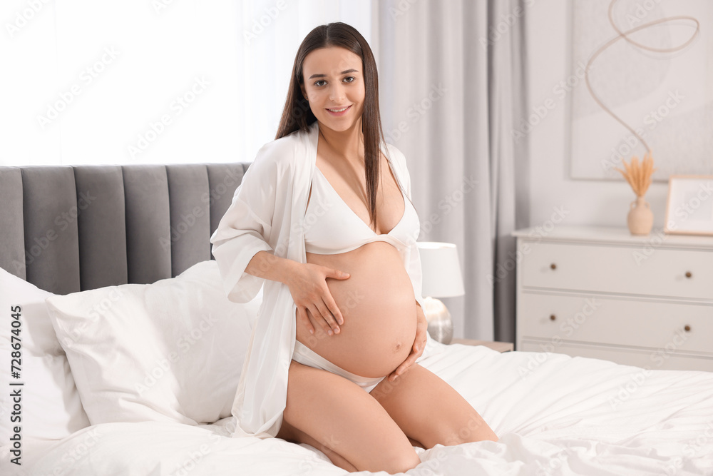 Beautiful pregnant woman in stylish comfortable underwear and robe on bed at home, space for text Beautiful pregnant woman in stylish comfortable underwear and robe on bed at home, space for text