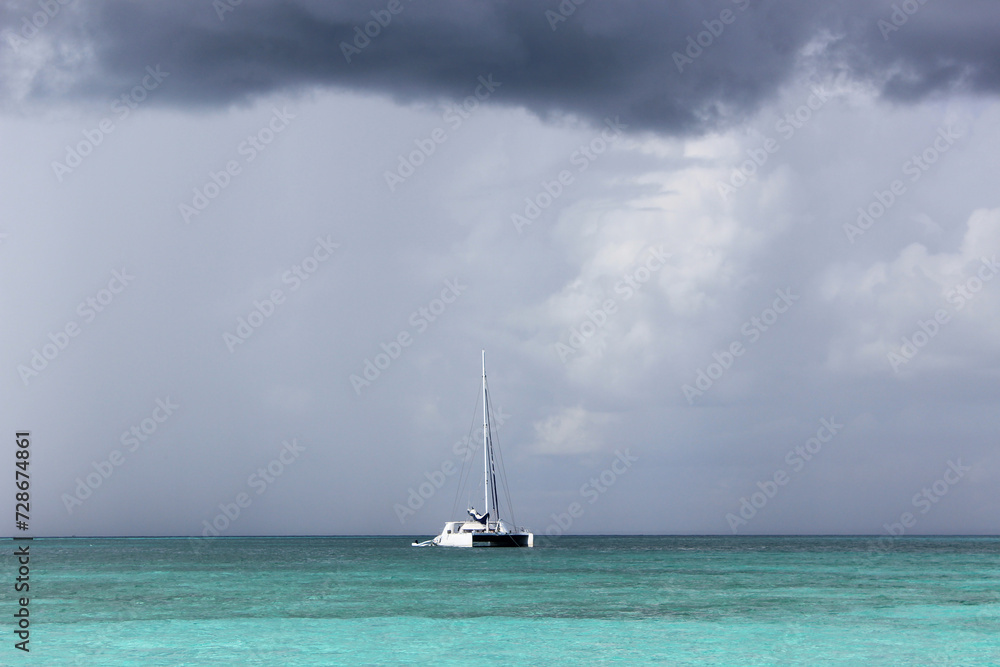 Fototapeta premium An impending storm in the Caribbean Sea. Turquoise water, white ship and storm clouds.