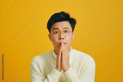 Nervous Asian man and biting nails in studio with oops reaction to gossip on Yellow background. Mistake, sorry and male overwhelmed by fake news, drama or secret with regret, shame or awkward