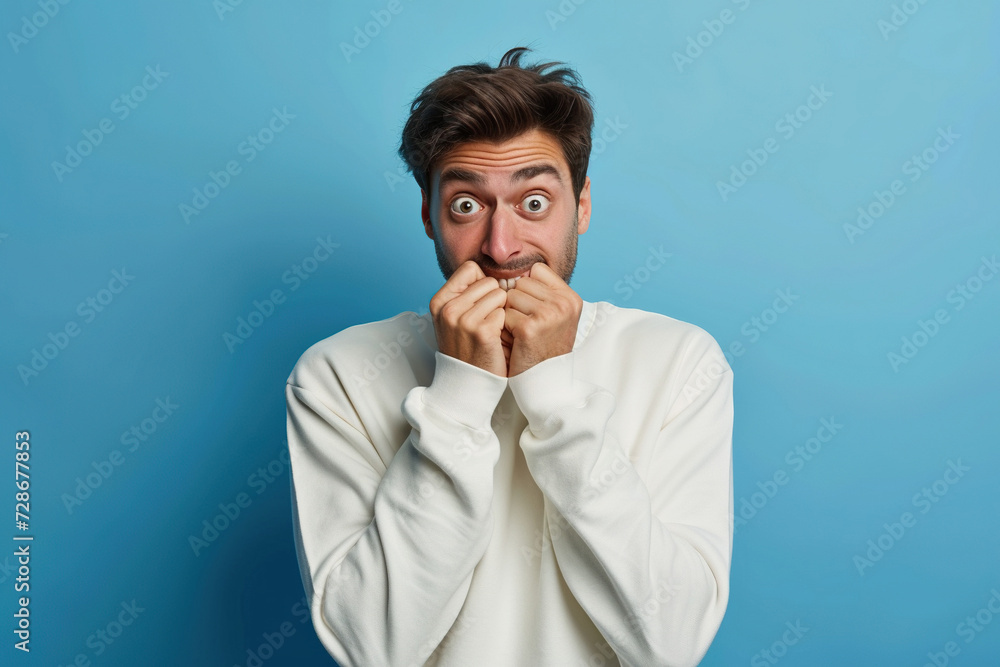 Nervous man and biting nails in studio with oops reaction to gossip on blue background. Mistake, sorry, fake news, drama or secret with regret, shame or awkward Nervous man and biting nails in studio with oops reaction to gossip on blue background. Mistake, sorry, fake news, drama or secret with regret, shame or awkward