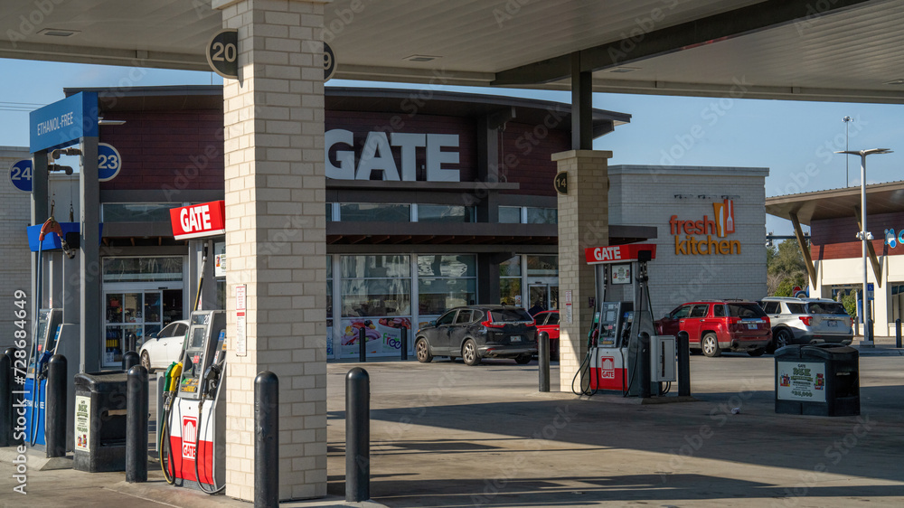 Vehicles refueling at a Gate gas station with service pumps and clear