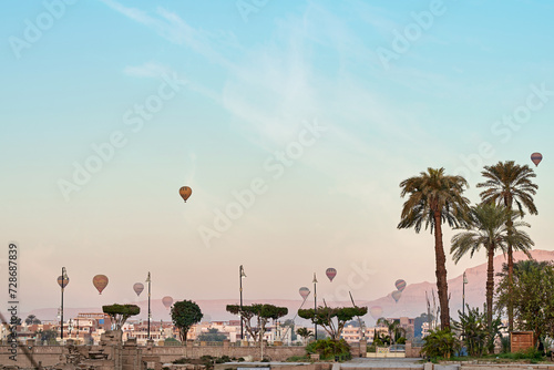 sun rise from luxor temple with palm tree and cloudy blue sky and hot air ballon in the background, Luxor, Egypt.