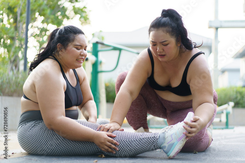 Close up shot of Asian oversized fat woman having an accident at her leg and her friend comes to help or support her. Oversized woman got an accident and her friend trying to do a first aid. photo